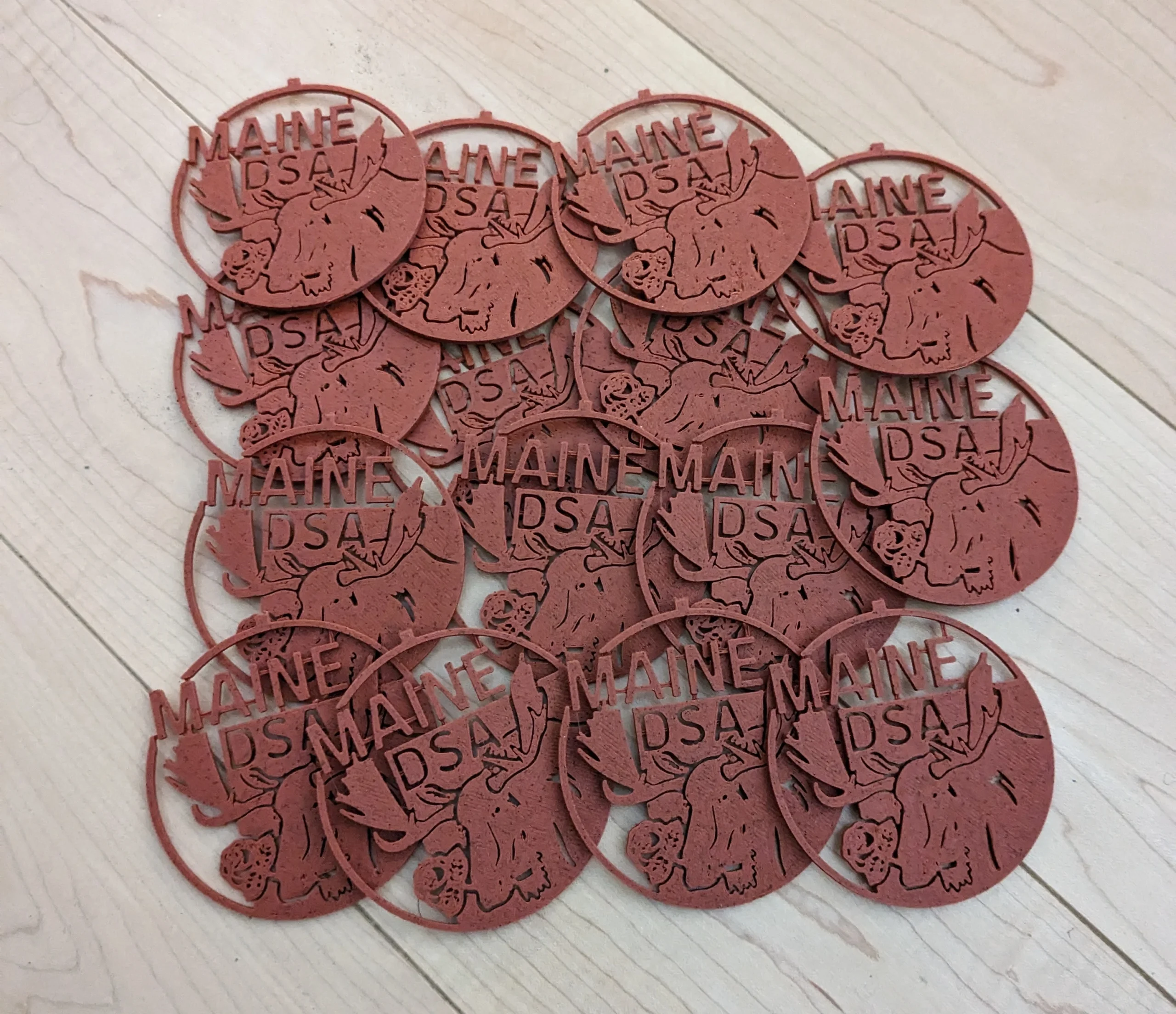 a pile of red plastic hanging ornaments in the shape of the maine dsa logo.